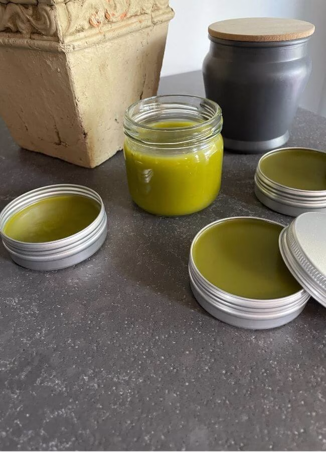 Homemade comfrey and cayenne pepper healing salve in a glass jar — a natural DIY pain relief balm made with herbs to soothe sore muscles and joint inflammation.