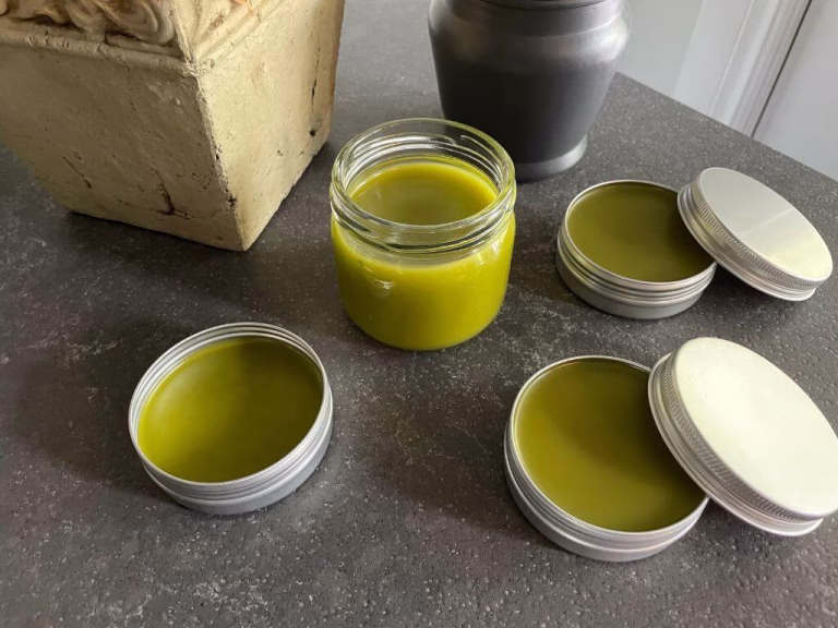 Homemade comfrey and cayenne pepper healing salve in a glass jar — a natural DIY pain relief balm made with herbs to soothe sore muscles and joint inflammation.