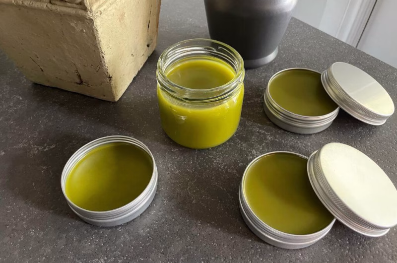 Homemade comfrey and cayenne pepper healing salve in a glass jar — a natural DIY pain relief balm made with herbs to soothe sore muscles and joint inflammation.