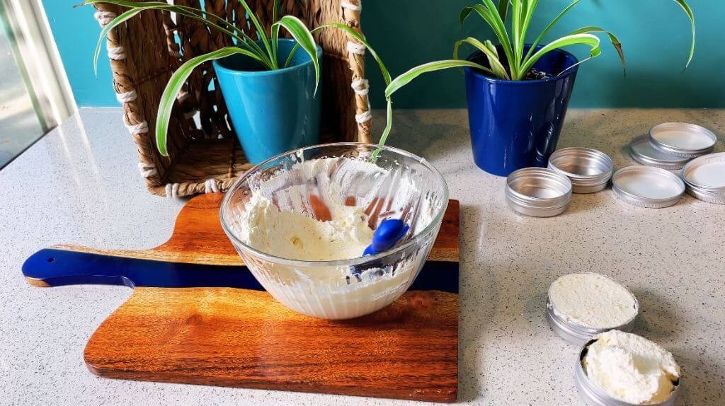 Whipping melted butters with essential oils using a hand mixer to create creamy DIY beard butter for conditioning beards